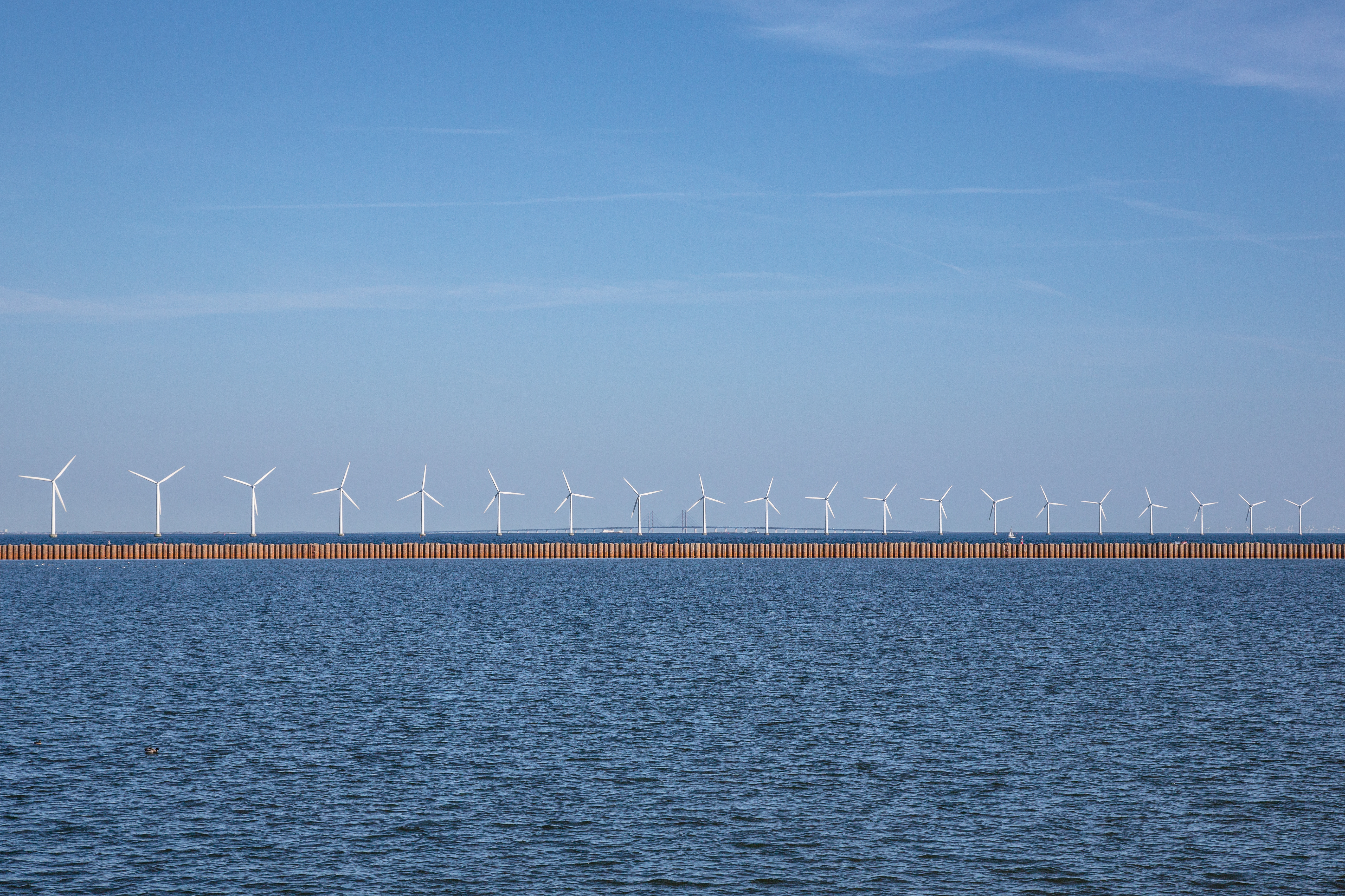 Wind turbines on line with blue water background