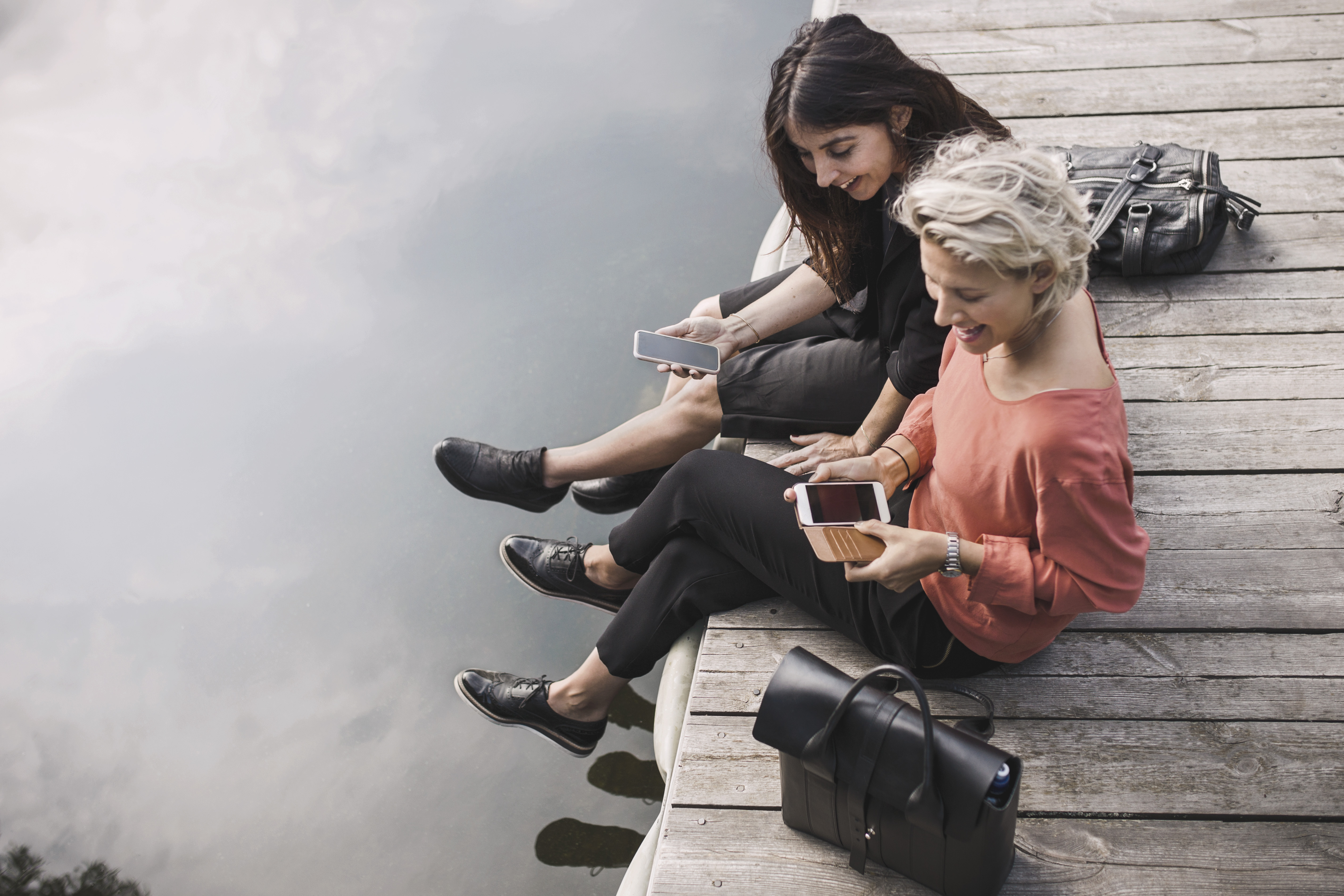 Businesswomen using phones by the lake